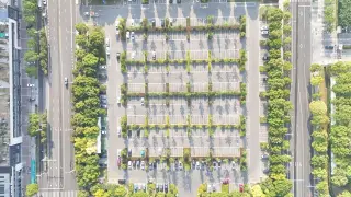 Ilustrasi: Pemandangan udara area parkir luas berpagar pepohonan dengan deretan mobil terparkir rapi.