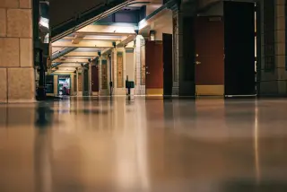 Ilustrasi: Lorong gedung kosong dengan deretan pintu kayu dan lantai mengilap.