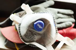 Ilustrasi: Masker respirator berkatup tergeletak di atas sarung tangan kerja.