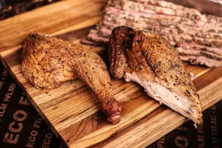 Ilustrasi: Potongan daging ayam panggang dan irisan daging asap di atas talenan kayu.