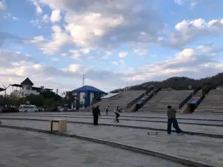 Pemandangan area publik berlantai paving dengan beberapa orang bermain skateboard dan bangunan bertingkat di latar belakang. Pelabuhan Labuan Bajo, Rabu (23/9/2…