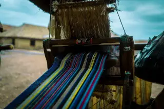 Ilustrasi: Alat tenun tradisional dengan benang aneka warna yang sedang dipintal di luar ruangan.