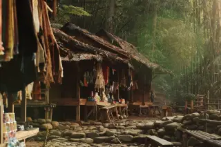 Ilustrasi: Deretan warung tradisional beratap rumbia di kawasan hutan bambu berbatu.