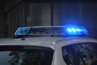 Ilustrasi: Lampu sirine biru menyala di atas atap mobil polisi putih.