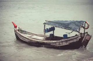 Ilustrasi: Sebuah perahu kayu tradisional bertenda jaring mengapung di atas air laut yang tenang.