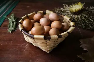 Ilustrasi: Telur-telur ayam tersusun di dalam keranjang anyaman di atas meja kayu.