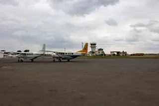 Ilustrasi: Dua pesawat perintis terparkir di apron bandara kecil di bawah langit berawan.