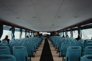 Ilustrasi: Deretan kursi penumpang berwarna biru di dalam kabin kapal feri.
