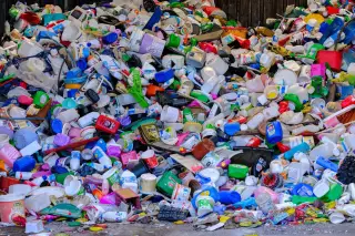 Ilustrasi: Tumpukan besar aneka wadah dan botol plastik bekas daur ulang berwarna-warni.