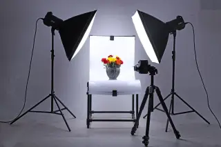 Ilustrasi: Pengaturan studio foto produk dengan dua lampu softbox, kamera di atas tripod, dan vas bunga.