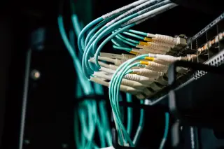 Ilustrasi: Kabel jaringan optik terpasang pada rak server di pusat data.