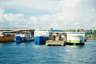Ilustrasi: Beberapa kapal feri bersandar di dermaga pelabuhan dengan latar langit cerah berawan.