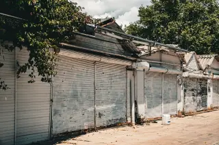Ilustrasi: Deretan kios pasar tua yang tertutup rapat dengan pintu gulung logam berkarat.