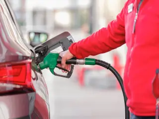 Ilustrasi: Petugas berbaju merah memasukkan nosel bahan bakar ke tangki mobil di SPBU.