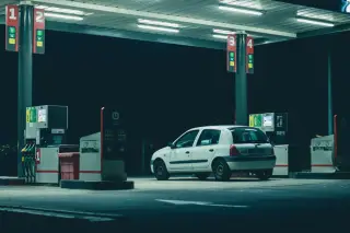Ilustrasi: Sebuah mobil putih terparkir di area pengisian bahan bakar umum pada malam hari.
