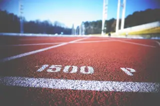 Ilustrasi: Sudut rendah lintasan lari atletik berwarna merah dengan garis marka 1500 meter.