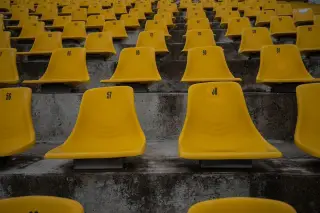 Ilustrasi: Deretan kursi tribun stadion berwarna kuning dengan nomor di atas undakan beton.