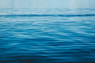 Ilustrasi: Permukaan air laut berwarna biru dengan riak-riak gelombang yang tenang.