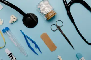 Ilustrasi: Berbagai peralatan medis seperti stetoskop, gunting, dan obat tersusun di atas latar biru.