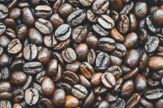 Ilustrasi: Bidikan makro tumpukan biji kopi sangrai berwarna cokelat tua.