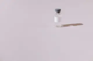Ilustrasi: Sebuah botol vial kecil transparan dengan label polos di atas latar belakang abu-abu.