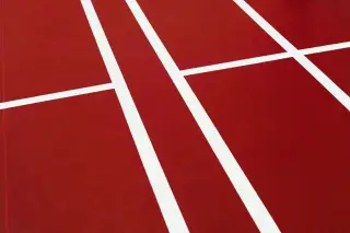 Ilustrasi: Garis-garis putih geometris di atas lantai lapangan olahraga berwarna merah.