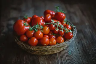 Ilustrasi: Tumpukan buah tomat merah segar di dalam keranjang anyaman di atas meja kayu.